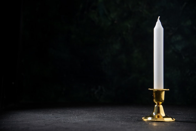Vista frontal de la vela blanca en soporte dorado sobre el negro