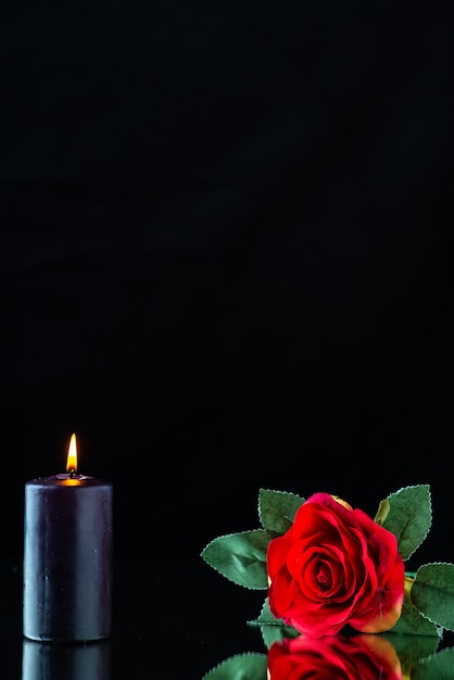 Vista frontal de la vela oscura con rosa roja sobre la superficie oscura