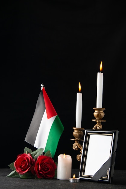 Vista frontal de velas encendidas con bandera palestina en superficie oscura