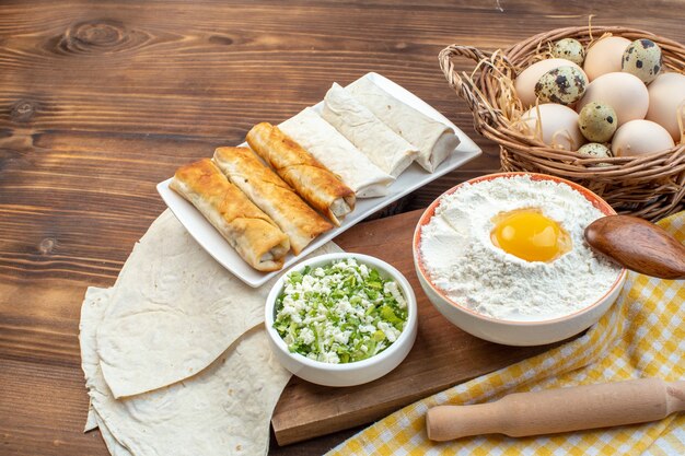 Vista frontal verdes rollos de pita con pasteles y huevos sobre fondo marrón cocinar alimentos hornear pastelería cocina carne pan