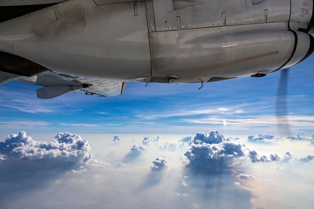 vista fuera de la ventana del avión Los motores del avión se ven arriba El fondo es una masa de nubes abajo durante el día Había una hermosa luz brillando a través