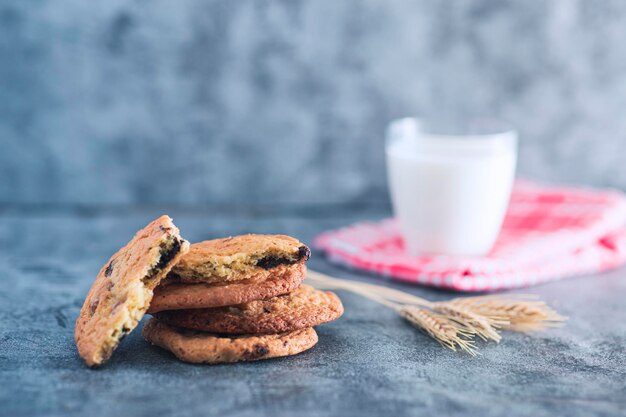 Vista de galletas caseras apiladas con un vaso de leche y foto de estudio de espiga de trigo