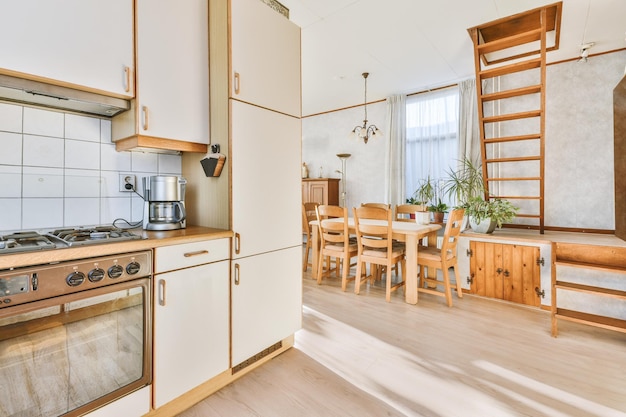 Vista geral de uma pequena cozinha de canto e área de jantar feita de móveis de madeira no piso de parquet de uma casa moderna