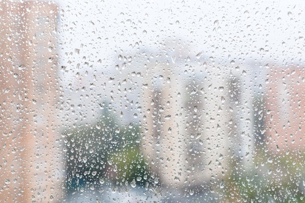 Vista de las gotas de lluvia en el cristal de la ventana de la casa urbana