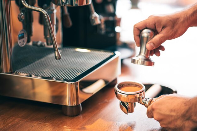 La vista de granos de café manipulados en un portafiltro de una elegante cafetería incluye espacio para copiar