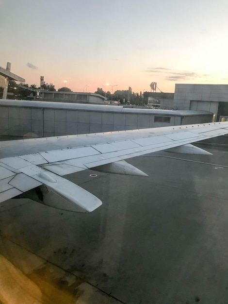 Vista de los hangares del aeropuerto desde el ojo de buey las ventanas del avión en el ala