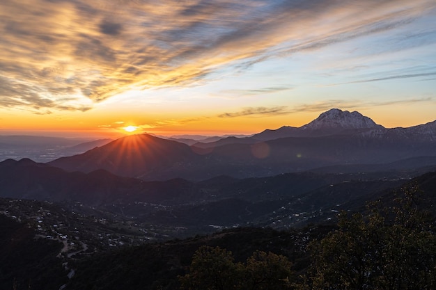 Foto vista de una hermosa puesta de sol con un colorido cielo nublado, un valle al pie de las montañas nevadas,