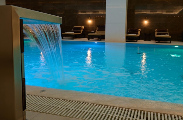 Vista de un hermoso interior con piscina termal cubierta con cascada en un salón de lujo de un centro de spa de bienestar
