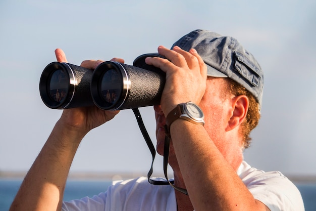 Vista de un hombre con binoculares mirando el horizonte del mar.