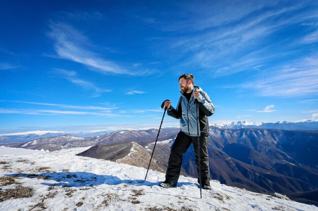 Vista de un hombre de pie en una montaña nevada contra el cielo