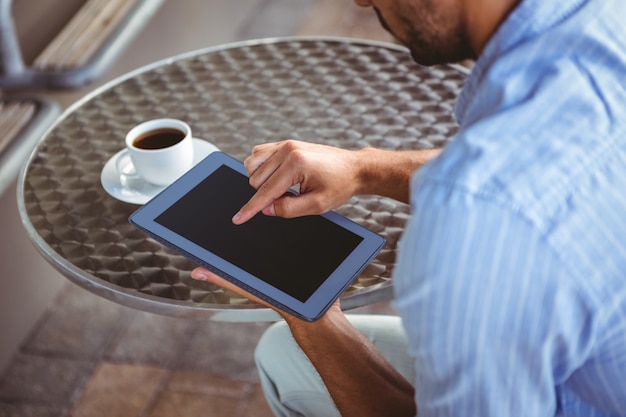 Vista de hombro del empresario atento usando una tableta fuera del café