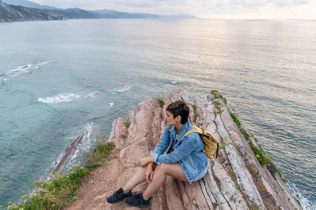 Vista horizontal de la mujer viajera aventurera turismo en los acantilados de Zumaia. Vista panorámica horizontal de la mujer que viaja en el país vasco. Personas y destino de viaje en España