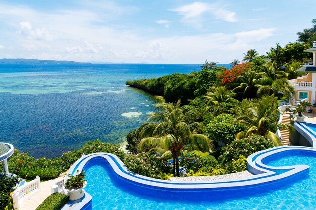 Vista desde un hotel con piscina infinita en la playa tropical y hermoso mar con botes