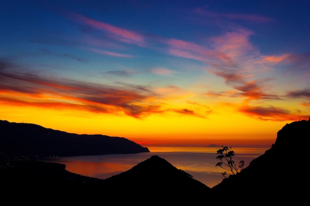 Vista idílica de silhuetas de montanhas contra o céu dramático durante o pôr-do-sol