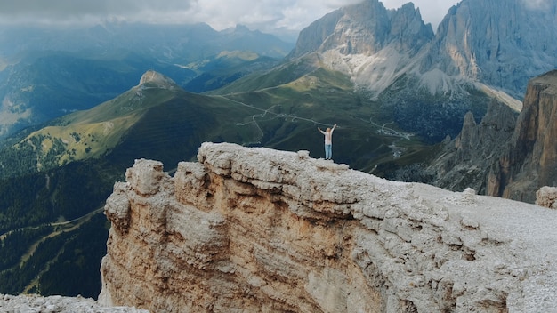 Vista incrível das montanhas com a mulher de pé no topo com as mãos estendidas. Sentindo liberdade e curtindo a natureza.