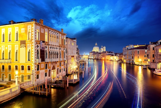 Vista incrível do Grande Canal e Basílica Santa Maria della Salute durante a noite com gôndolas e nuvens de tempestade Veneza Itália