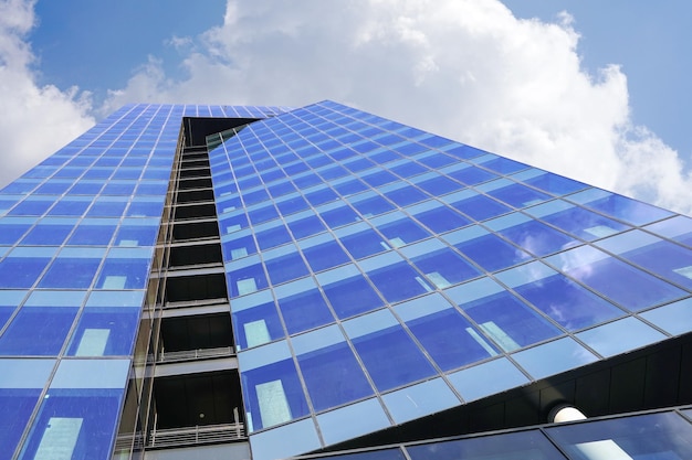 Vista inferior através de um moderno arranha-céu alto até o céu de nuvens azuis Fragmento abstrato de arquitetura