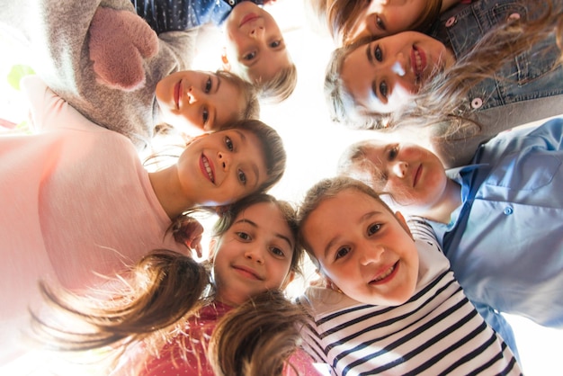 Vista inferior de caras de niña en la ronda. Compañeros de escuela en el descanso