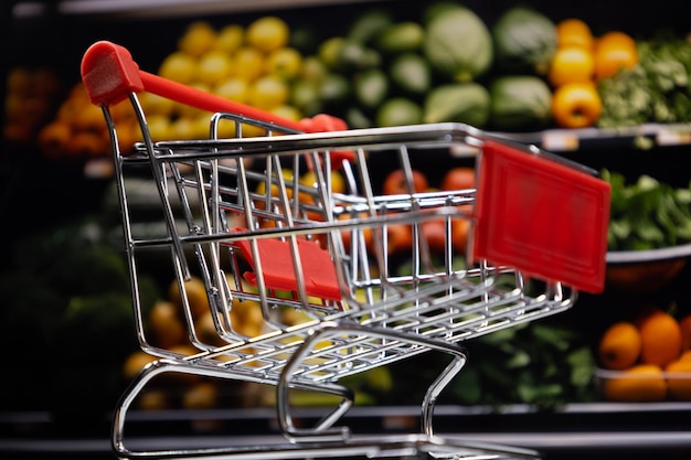 Vista inferior del carrito de compras con estantes de frutas borrosos en el fondo