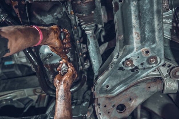 vista inferior das mãos de um mecânico consertando um carro