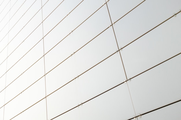 Vista inferior de la pared de metal blanco de un edificio hecho de pequeñas láminas metálicas enderezadas