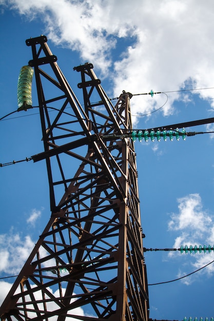 Vista inferior de un poste de metal de una línea eléctrica con multitud de cables eléctricos.