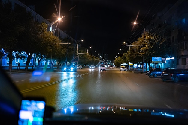 Una vista desde el interior del automóvil que conduce de noche en la carretera de tráfico de la ciudad