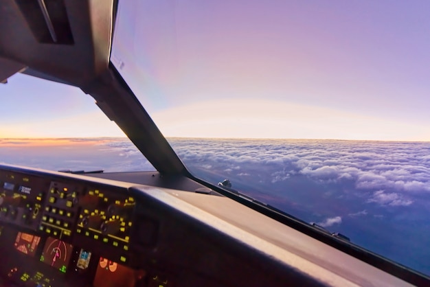 Vista desde el interior de la cabina en el asiento del copiloto cuando el avión vuela a gran altura sobre las nubes en el cielo