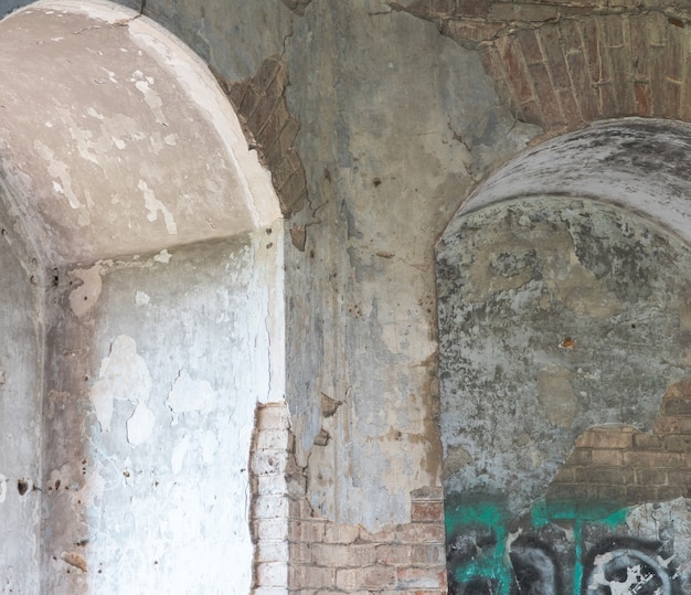Vista interna de um prédio antigo abandonado com um arco na parede