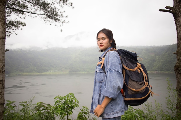 Vista de la joven mujer asiática de pie delante del bosque del lago