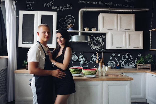 Vista desde el lado de una hermosa mujer embarazada de pie cerca de un esposo cariñoso en la cocina Un hombre amado cocinando la cena para una esposa adorable en casa Futura madre y padre esperando un bebé Concepto de amor