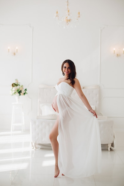 Vista desde el lado de la mujer embarazada en un hermoso vestido blanco