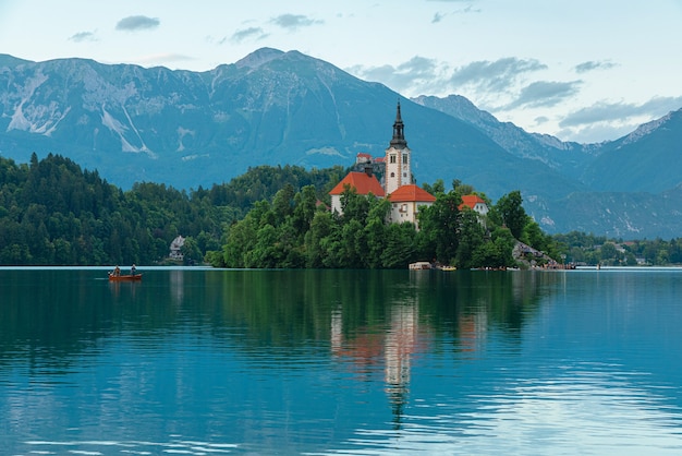 Vista del lago Bled de la isla con la iglesia de la Asunción de María en el hermoso lago con barco en Alpes Julianos, Eslovenia