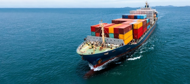 Vista lateral aérea del buque de carga que transporta contenedores y se ejecuta para exportar mercancías desde el puerto del patio de carga a otro buque de transporte de carga del concepto oceánico