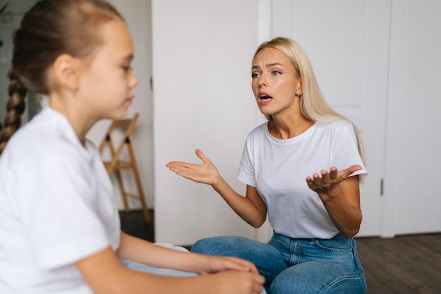 Foto vista lateral aproximada de uma jovem mãe emocional zangada repreendendo o grito de voz e gesticulando com as mãos para a filha teimosa e difícil em casa