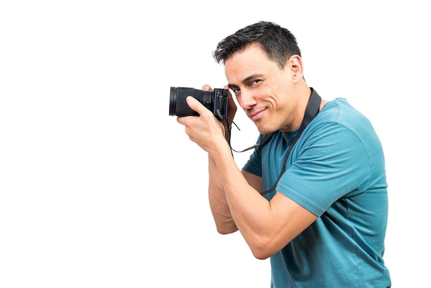 Vista lateral del astuto fotógrafo masculino tomando fotos en una cámara fotográfica profesional sobre fondo blanco aislado