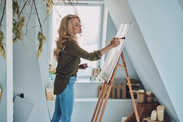 Foto vista lateral, de, atractivo, mujer joven, pintura, en, estudio de arte