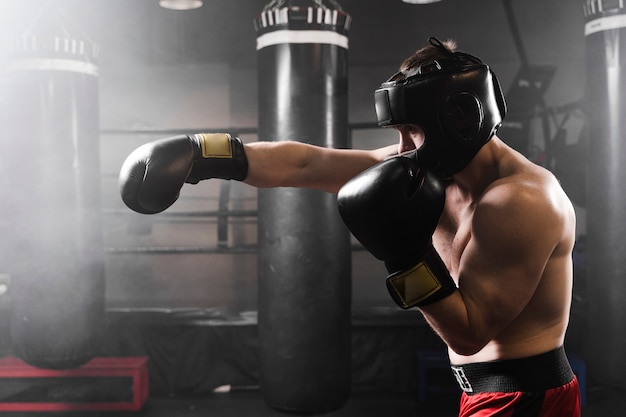 Vista lateral boxer con guantes negros de entrenamiento
