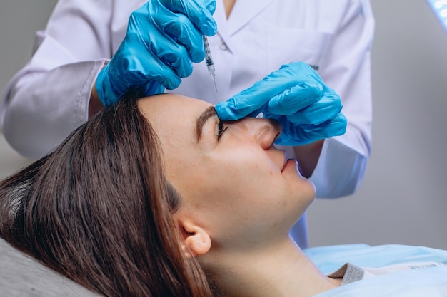 Una vista lateral de la cara suave de una mujer joven que recibe una inyección antienvejecimiento en un salón de belleza de esteticista.