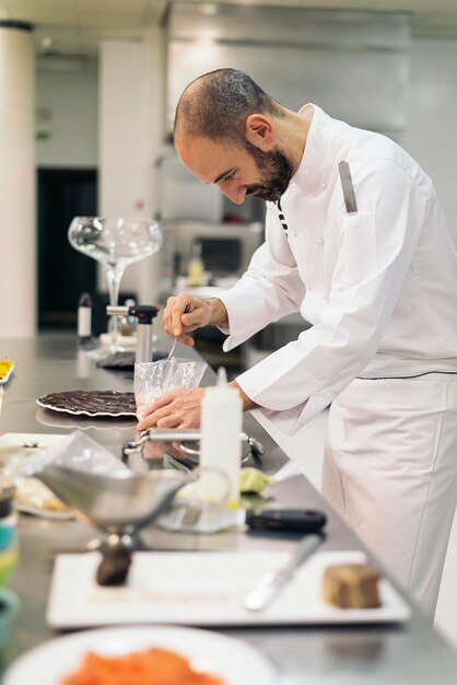 Foto vista lateral del chef preparando comida en una cocina comercial