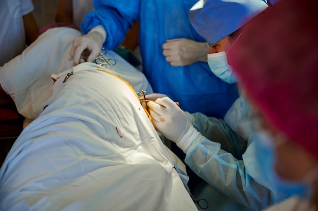 Vista lateral de un cirujano cosiendo una herida con un instrumento quirúrgico