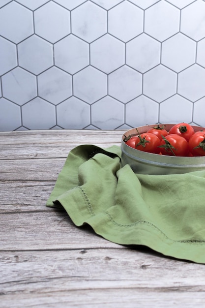 Vista lateral de un conjunto de tomates cherry en recipiente de metal con tela verde