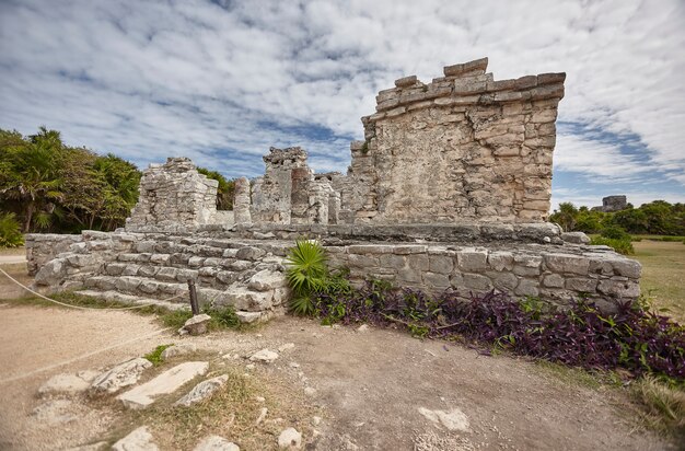 Vista lateral das ruínas de um pequeno templo maia no complexo de tulum, no méxico, tirada ao pôr do sol.