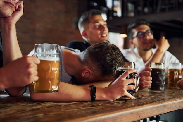 Vista lateral de amigos com cerveja Pessoas em roupas casuais sentadas no pub