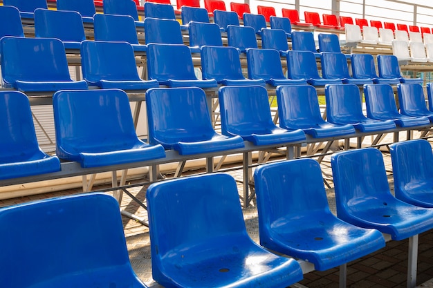 Vista lateral de assentos plactic azuis e vermelhos na arquibancada do estádio de esporte