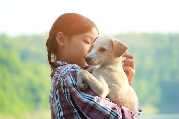 Foto vista lateral de menina carregando cachorro contra árvores