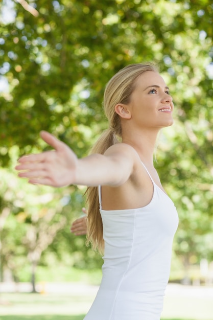 Foto vista lateral de mulher atraente e alegre fazendo yoga espalhando seus braços