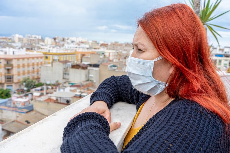 Foto vista lateral de mulher usando máscara enquanto está de pé no terraço do edifício