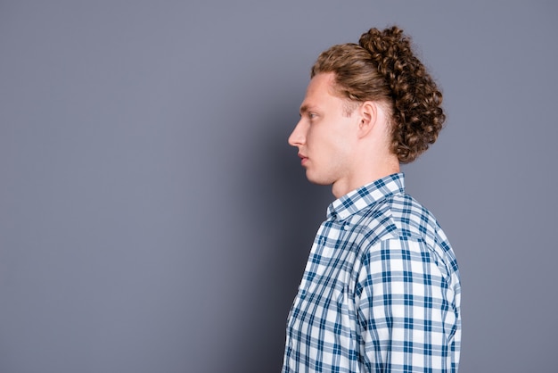 Um homem sério e bonito com cabelo encaracolado e camisa xadrez