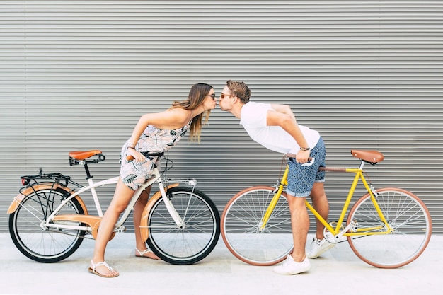 Vista lateral de um casal com bicicletas a beijar-se ao ar livre
